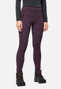 Lila leggings med hög midja, böjda sömmar och sidofickor, i kombination med svarta vandringskängor med röda snören.