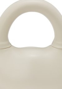 Kremfarvet lædertaske med en glat, rund håndtag, minimalistisk design og blød tekstur. Enkel og moderne æstetik.