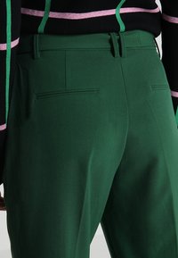 Zelené kalhoty na míru s plochým předním dílem, dvěma zadními kapsami a hladkým textilním materiálem. Navrženy s poutky na opasek a slim fit střihem.