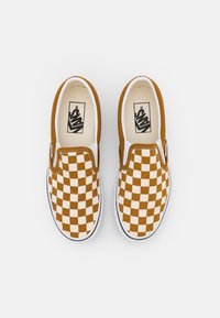 Bruna och krämfärgade rutiga slip-on skor med överdel av tyg, vit gummisula och Vans-logga på innersulan.