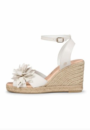Sandalia blanca de cuña con correa en el tobillo, tacón de yute trenzado y una gran flor decorativa en la correa del dedo.