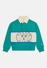 Πράσινη μπλούζα πόλο με μακριά μανίκια, με μπεζ γιακά και μπεζ πανέλα στο μπροστινό μέρος που φέρει το κείμενο «Tennis Club» και γραφικό με σταυρωτές ρακέτες τένις.