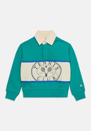 Πράσινη μπλούζα πόλο με μακριά μανίκια, με μπεζ γιακά και μπεζ πανέλα στο μπροστινό μέρος που φέρει το κείμενο «Tennis Club» και γραφικό με σταυρωτές ρακέτες τένις.