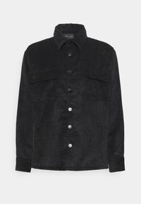 Giacca camicia di velluto a coste nera con chiusura a bottoni, due tasche sul petto, colletto classico e tessuto testurizzato. Bottoni in tono argento come dettaglio.