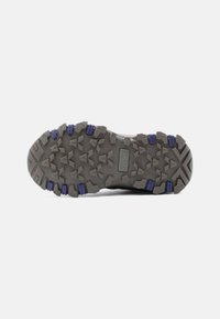 Γκρ ι λαστιχένια σόλα παπουτσιού με βαθιές αυλακώσεις, διακοσμημένη με μωβ λεπτομέρειες και ζιγκ-ζαγκ μοτίβο, σχεδιασμένη για πρόσφυση και ανθεκτικότητα σε εξωτερικές συνθήκες.