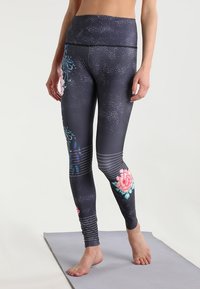 Korkeavyötäröiset legginssit tummanharmaana, joissa on vaaleanpunaisia ja sinisiä kukkakuoseja. Niissä on teksturoitu pinta ja vaakasuorat raidat nilkoissa.