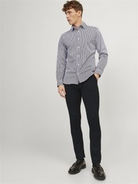 Blau-weiß gestreiften Hemd mit Knöpfen und langen Ärmeln, kombiniert mit engen schwarzen Hosen und schwarzen Schuhen. Glatter Stoff und klassisches Kragen-Design.