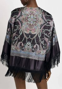 Zwarte satin kimono-achtige kledingstuk met kleurrijk paisleypatroon, franjes aan de onderkant en wijde mouwen. Bevat ingewikkelde ontwerpelementen en texturen.