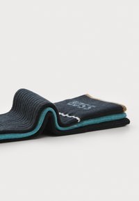 Rippensocken in Dunkelblau, umgeklappt, mit einem türkisfarbenen Akzent oben und einem beigen Rand, und einem weißen Textdesign auf einer Seite.