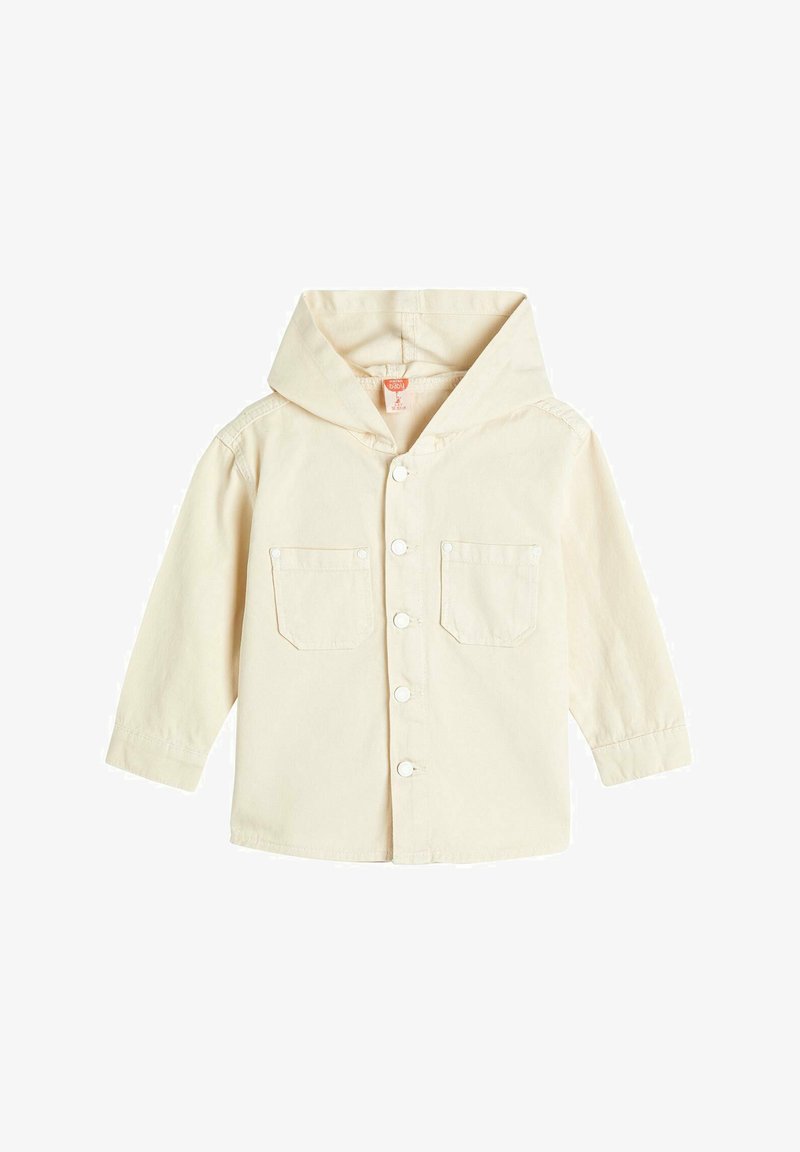 Lys beige hættetrøje med knapper foran, to brystlommer og lange ærmer. Designet i et blødt, åndbart materiale med en afslappet pasform.