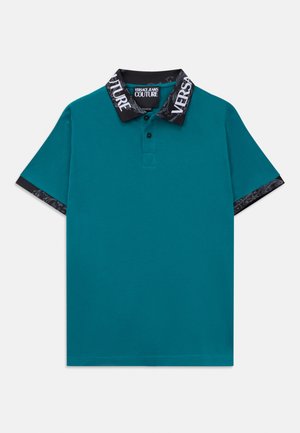 Tirkizna majica s kratkim rukavima i crnim ovratnikom i manžetama, s bijelim natpisom Versace Jeans Couture i ukrasnim uzorcima.