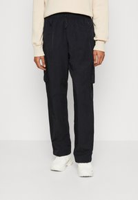 Pantalones cargo ligeros y negros con cintura elástica y cordón, que cuentan con bolsillos laterales y un acabado liso y texturizado.