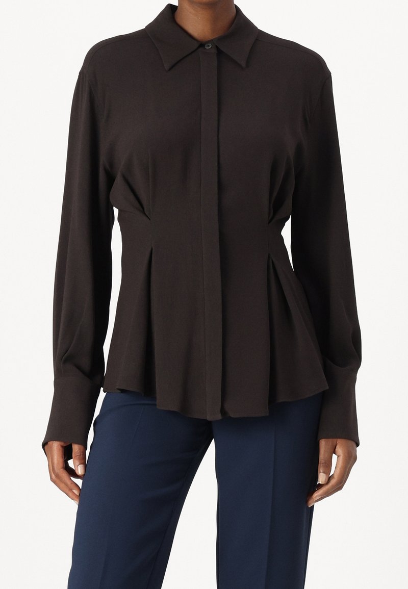 Chemise noire à boutons, avec un col, des manches longues et des détails plissés à la taille, fabriquée dans un tissu lisse à finition mate.