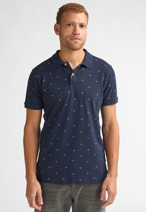 Polo bleu marine à manches courtes, orné de petits motifs d'oiseaux rouges, avec une patte de boutonnage à deux boutons et une texture douce. Porté avec un jean gris.