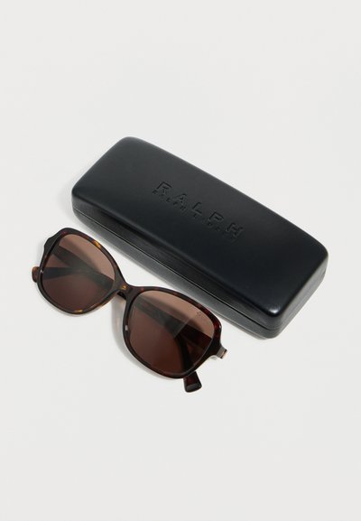 Γυαλιά ηλίου με ταρταρούγα πλαίσιο και καφέ φακούς, δίπλα σε μαύρη δερμάτινη θήκη γυαλιών ηλίου με την επωνυμία Ralph Lauren, πάνω σε λευκή επιφάνεια.