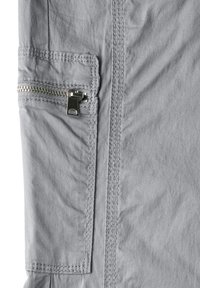 Dettaglio di tasca in tessuto grigio con zip in metallo argento e cuciture visibili. La texture appare liscia con una leggera lucentezza.
