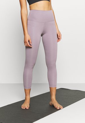 Leggings a vita alta di colore lavanda realizzati in un materiale liscio e elastico, con un design aderente, che si fermano poco sotto il polpaccio.