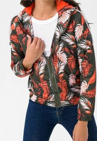 Pimeänvihreä vetoketjullinen bombarintakki, jossa rohkea punavalkoinen trooppinen lehtikuvio. Takissa on oranssi vuori ja joustavat hihansuut.