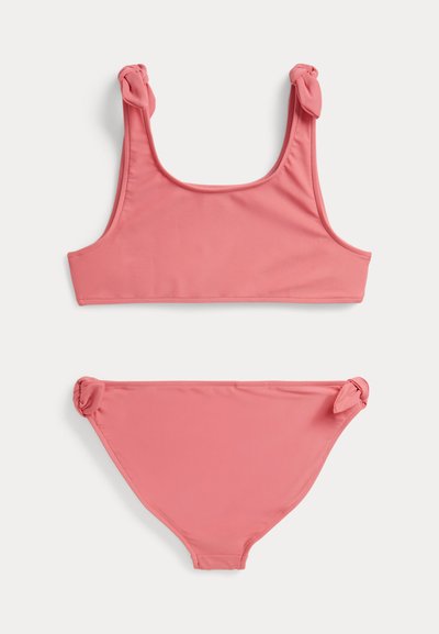 Σετ ροζ μπικίνι με τοπ τετράγωνης λαιμόκοψης και διακοσμητικές κόμπους στα τιράντες, καθώς και κάτω μέρος μπικίνι με αντίστοιχα λεπτομερή κόμπους.