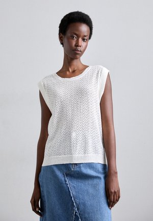 Top senza maniche lavorato a maglia bianco con un motivo testurizzato, scollo rotondo e una vestibilità ampia, abbinato a una gonna di jeans blu.