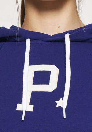 Fioletowa bluza z kapturem z dużym, kremowym logo "P" z akcentem w postaci gwiazdki. Białe sznurki z fakturą żebrowaną. Miły w dotyku materiał.