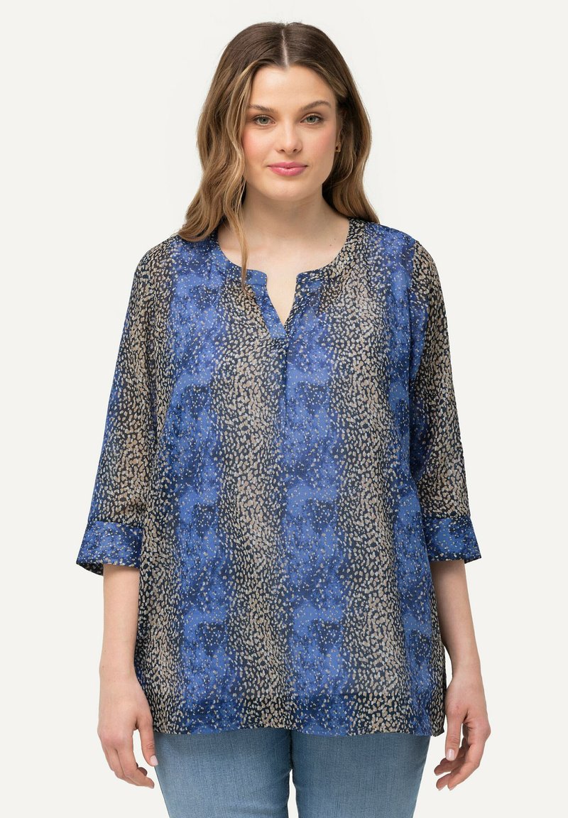 Blusa blu e beige a fantasia con maniche a tre quarti, scollatura a V e tessuto leggero e trasparente. La texture notevole crea un interesse visivo.