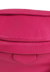 Felle roze leren tas met een gestructureerde afwerking, een ronde flapsluiting en een driehoekige accent aan de voorkant. Compact en soepel ontwerp.