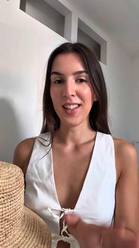 Cappello di paglia con una parte superiore piatta e rotonda e una visiera larga, esposto accanto a una persona che indossa una maglietta bianca con un dettaglio a fiocco sul colletto.