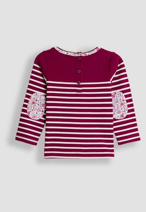Maglia a maniche lunghe di un intenso bordeaux con strisce bianche, con toppe a gomito floreali e un'apertura con tre bottoni nella parte posteriore.