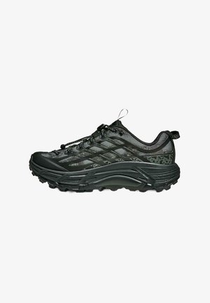 Zapatilla de trail running negra con suela robusta, parte superior de malla, sistema de cordones seguro y tiradores en el talón y la lengüeta.