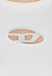 T-shirt bianco in cotone con un ritaglio ovale testurizzato con contorno ricamato e un piccolo logo al centro. Tessuto liscio, collo a giro.