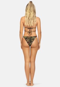 Strój bikini z czarnym topem wiązanym z tyłu i wzorzystymi, niskimi majtkami w zielone, brązowe i żółte wzory. Teksturowany materiał.