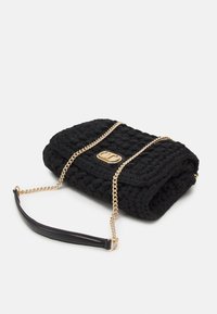 Borsa a mano nera in crochet con tracolla in catena dorata e dettaglio in pelle. Presenta un design piegato e un emblema dorato sulla parte anteriore.