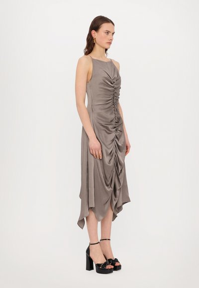 Gray satin dress with a scoop neckline, ruched front, and asymmetrical hemline. Paired with black heeled sandals featuring a bow accent.