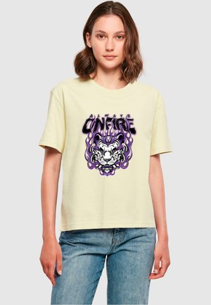 Gul t-shirt med kort ärm som har en grafisk bild av ett tigerns ansikte omgett av lila lågor och texten "ALWAYS UNFIRE."