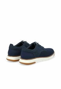 Par de zapatos casuales azul marino con cordones, suelas blancas y detalles en la suela marrón, mostrados desde la parte trasera y lateral.