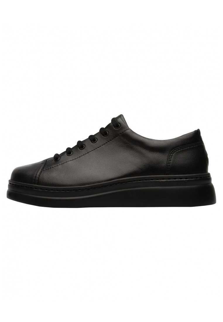 Black leather sneaker with a rounded toe, flat sole, and six eyelets for laces. Minimalistic design with subtle stitching detail.
