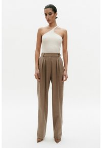 Crème ribbelgebreide top met één schouder, gecombineerd met beige geplooide broek met hoge taille, met een getailleerde pasvorm en een enkellange stijl.