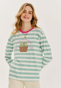 Dlhý rukáv pruhované tričko vo svetlozelenej a bielej farbe, s ružovým výstrihom a grafikou kociek na rastliny s vyšívaným textom.