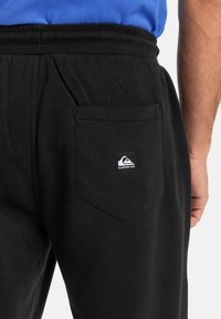 Pantalones de chándal negros de algodón, con cintura elástica, bolsillos laterales y un bolsillo trasero con un parche del logo.