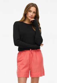 Sort ribbet langærmet sweater parret med lyserøde shorts med snørebånd i taljen, der har en afslappet pasform og opretstående kant.