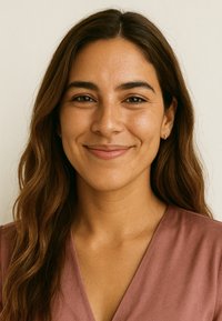 Porträtt av en kvinna med långt, vågigt brunt hår, klädd i en dammig rosenfärgad V-ringad topp, mot en neutral bakgrund. Diskreta örhängen synliga.