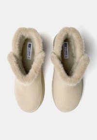 Pantofole beige senza lacci con pelliccia morbida attorno all'apertura, etichettate Pull&Bear Collection, taglia 37, su uno sfondo bianco.