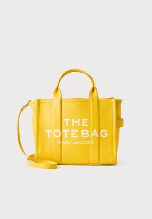 Kollane pebble nahast ostukott kahekordsete käepidemete, eemaldatava õlarihmaga ja selgelt valgete kirjaga: "THE TOTE BAG MARC JACOBS" ees.