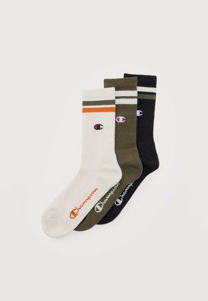 Tre par Champion crew-sokker i hvit, olivengrønn og svart, hver med striper og logo på siden og øvre mansjett.