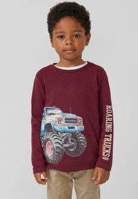 Burgunderfarbenes Langarmshirt mit einem Grafikdruck eines blauen Monstertrucks auf der Vorderseite und dem Schriftzug "ROARING TRUCKS" in Weiß auf dem Ärmel.