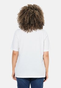 T-shirt en coton blanc à manches courtes, encolure arrondie et coupe ample, vue de dos. Ourlet plat et texture douce.