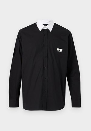 Black long-sleeve button-up shirt with contrasting white collar and chest pocket featuring white sunglasses logo and "KARL LAGERFELD" text.