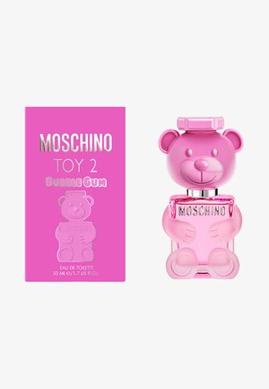 Bouteille en forme d'ours rose avec des caractéristiques arrondies et un visage souriant. Capuchon argenté et logo, accompagnée d'une boîte rose vif avec un design d'ours.