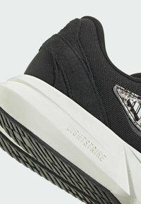 Čierna športová obuv s textúrovaným zvrškom a semišovými akcentmi, bielym LIGHTSTRIKE medzipodrážkou a vzorovanou čiernou gumovou podrážkou.